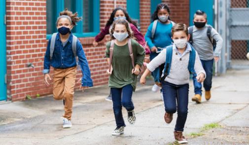 young children with masks covering their noses and mouths run towards the camera