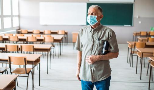 teacher wearing mask in empty classroom