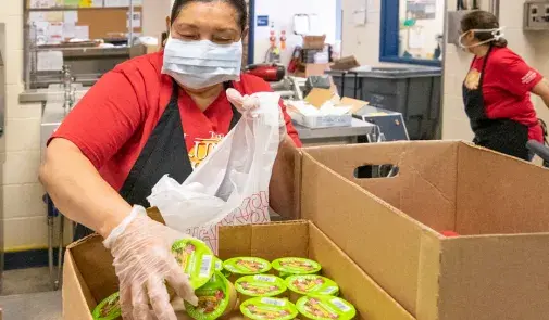 a woman. Alma Garcia, sorts food in a cardboard box