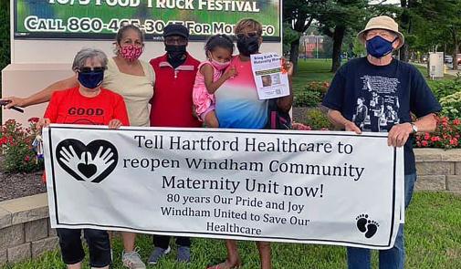 people holding sign urging hartford healthcare to reopen the windham maternity unit