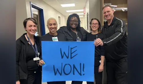 nurses holding up a blue sign that reads WE WON