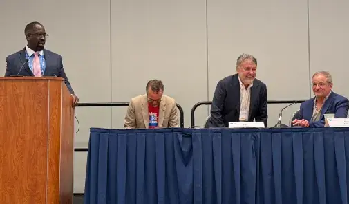 Speaker at podium with panel to his left