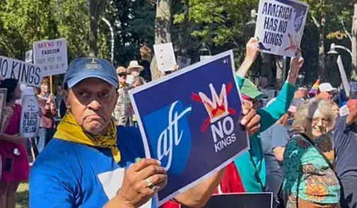 AFT members march. Sign reads "No Kings"
