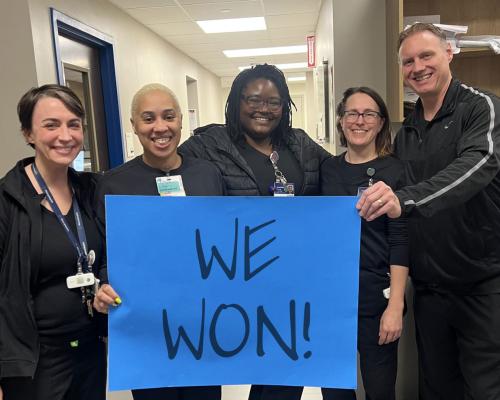 nurses holding up a blue sign that reads WE WON