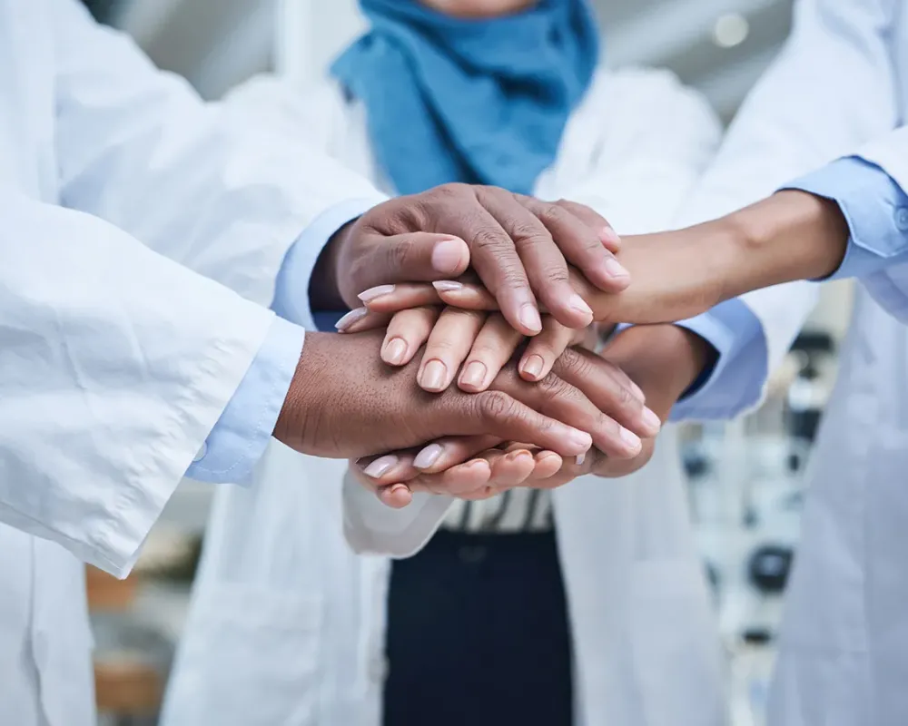 Photo of three doctors joining hands to work together