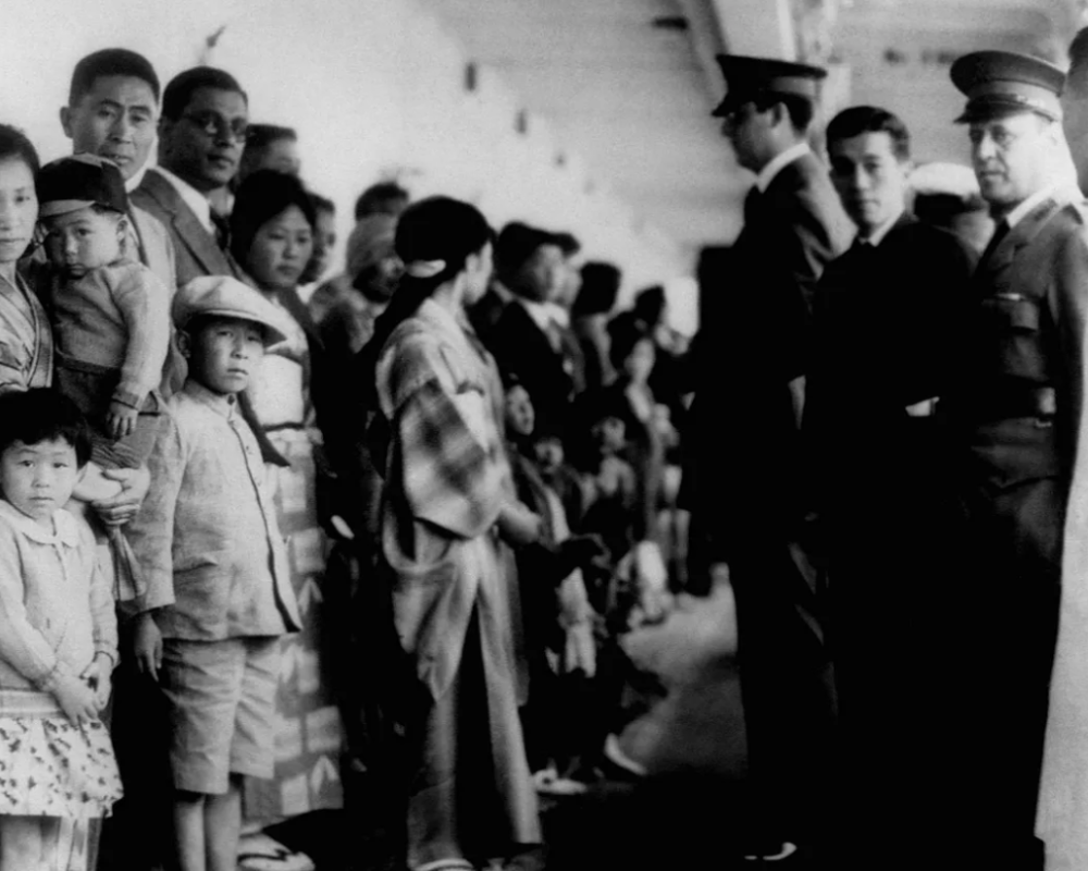 Un grupo de inmigrantes asiáticos en Angel Island, en blanco y negro, vía Getty Images
