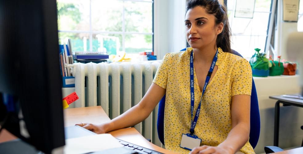 teacher looks at resources on a classroom computer