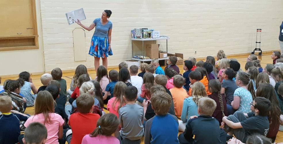 Photo of adult reading to a room full of children