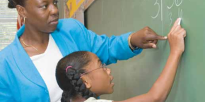 Photo of teacher and student writing on chalkboard