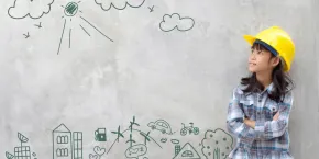 Foto de un niño con casco mirando ideas dibujadas en una pizarra