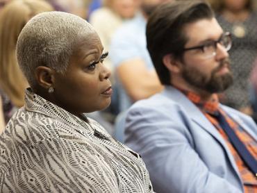 two public school teachers, an african american woman and a white man, sit and listen