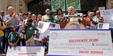 demonstrators holding giant cancelled checks