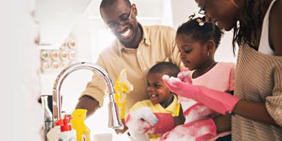 una familia negra feliz lava los platos juntos