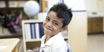 Pequeño muchacho latino sonriente en aula