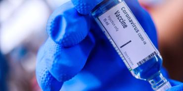 vaccine being given by hand in blue glove