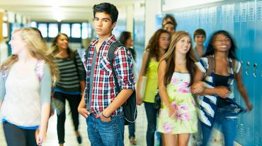 young man in high school hallway with blurry students in background