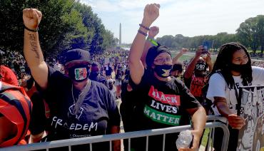 people raise their fists with the washington monument in the background