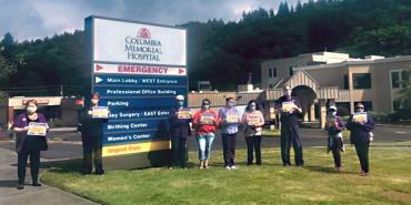 nurses stand outside with hospital sign