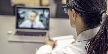 person with ponytail hairstyle watches person on computer