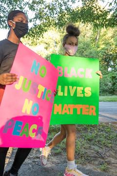 Youths hold signs reading "No Justice No Peace" and "Black Lives Matter"