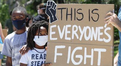 dos pequeños niños negros con máscaras de protección codiciosas y sostienen un cartel que dice que esta es la pelea de todos