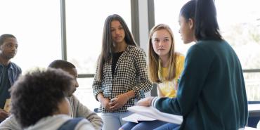 Photo of a teacher speaking with students in class