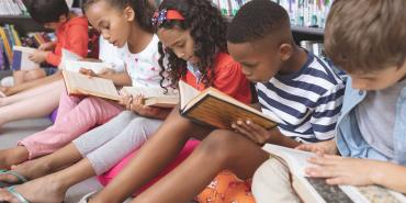 Foto de niños leyendo libros juntos.