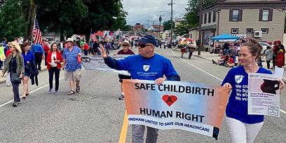 people walk with sign that says safe childbirth a human right