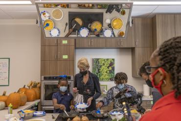 Foto de estudiantes realizando un proyecto práctico en una cocina.