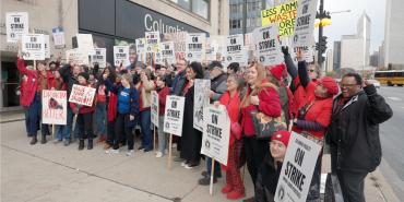 teachers and students on strike holding signs in a group photo