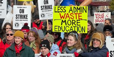 Photo of Columbia College Faculty Union members on the picket line. Signs read "Columbia Faculty On Strike. Unfair Labor Practices. Illinois Federation of Teachers, Local 6602. IFT, AFT, AFL-CIO", "Less Admin Waste, More Education", and "Value Your Students"