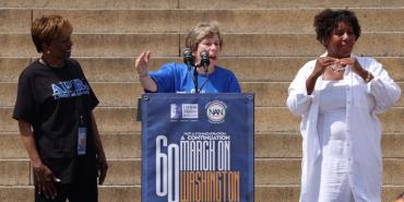 Foto: Randi Weingarten habla antes de la Marcha sobre Washington flanqueada por el presidente de APRI, Clayola Brown (izquierda) y un intérprete (derecha).