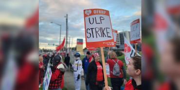 Photo of striking OFNHP workers. Sign reads "OFNHP - ULP Strike"