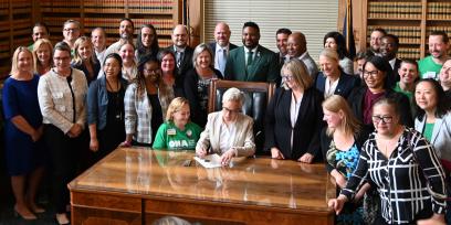 Foto de la gobernadora de Oregón, Tina Kotek, firmando el proyecto de ley 2697 de la Cámara de Representantes con miembros de ONA y OFNHP