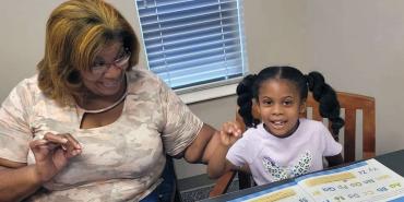 Erika Bryant celebra nuevas habilidades de lectura con un niño al que está dando clases particulares.