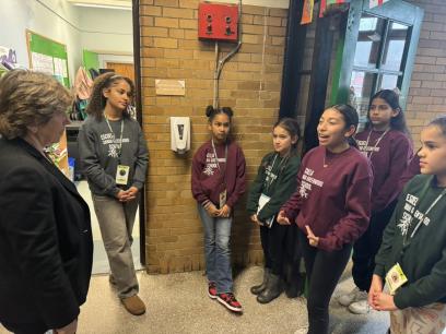 AFT President Randi Weingarten listening to students speaking in a school hallway