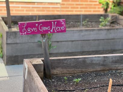small sign reading "love grows here" in a planter box