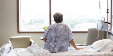 Getty Images Paciente de hospital sentado en la cama frente a la ventana