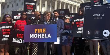 El presidente de la AFT, Randi Weingarten, habla con la prensa en una conferencia al aire libre rodeada de carteles y personas que apoyan el movimiento FIRE MOHELA.