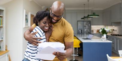 stock photo: black couple (male, female) hug while looking at a document