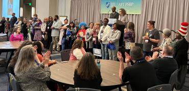 PSRP co-chairs Carl Williams and Sarah Wofford, at lectern, stand with members of the program and policy council.