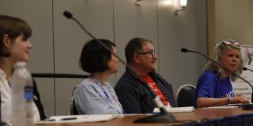 Four speakers are seated at a table. Clara Conover, Belle Boggs, and Rob Kilgore (left to right) look at Laureen LeFever (far right) as she speaks about mobilizing student voters on campus.