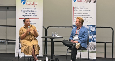 Two speakers sit on a stage, talking about organizing to protect academic freedom.