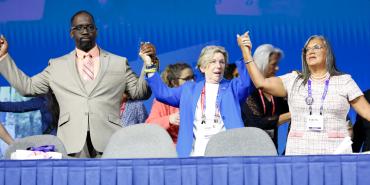 Re-elected officers Fedrick Ingram, Randi Weingarten and Evelyn DeJesus hold hands onstage.