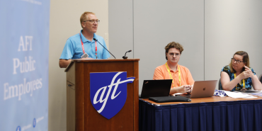 A member of AFT Public Employees speaks from behind a podium at the divisional meeting.