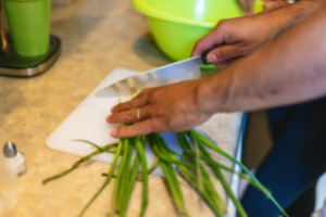 Foto de persona cortando verduras.