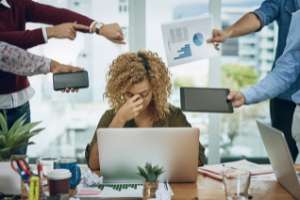 Foto de una mujer estresada trabajando en una computadora portátil con muchas personas exigiendo atención