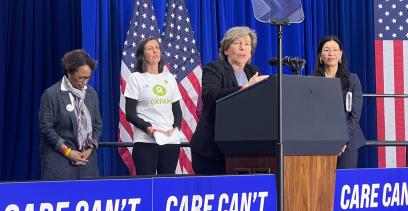Imagen del presidente de popa Randi Weingarten en el escenario hablando en el podio con tres adultos detrás de ella.