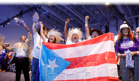 Victor Bonilla, President of Asociación de Maestros de Puerto Rico (AMPR) and AMPR members holding a Puerto Rican flag and raising their fists at AFT’s 2026 Convention, July 16, 2026.